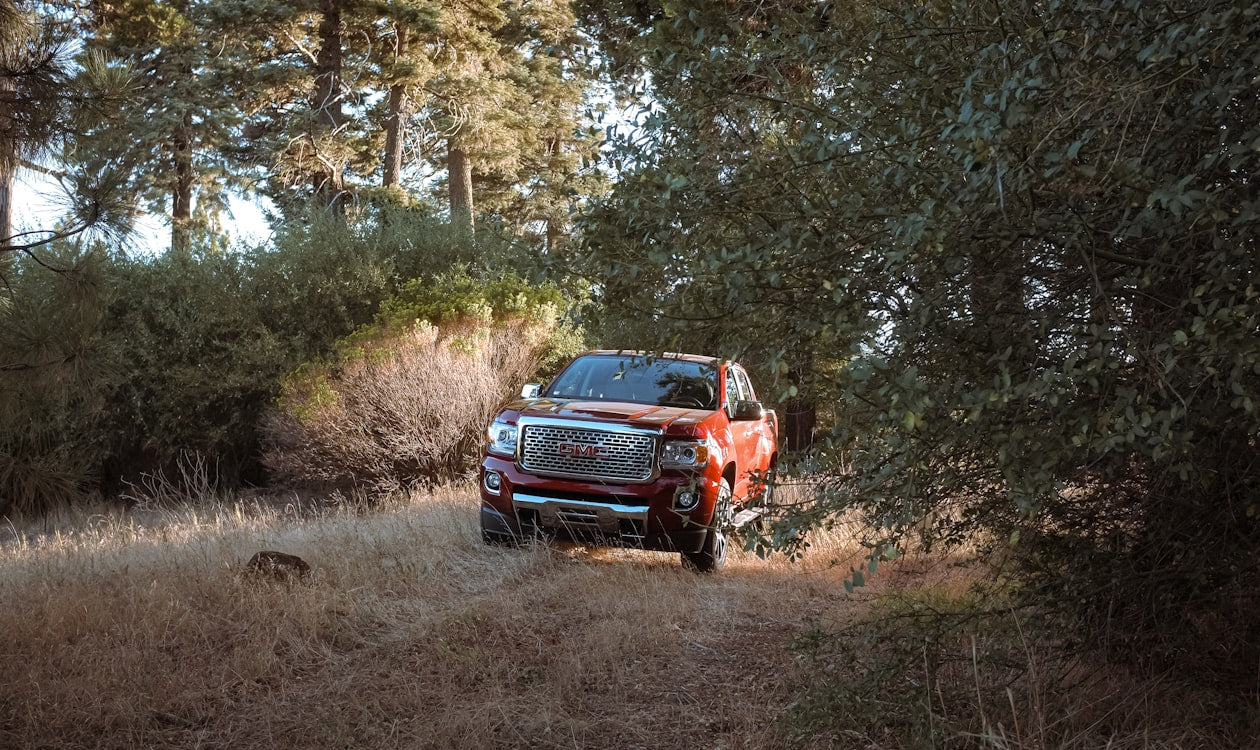 Red GMC Canyon Denali exploring a rugged forest trail