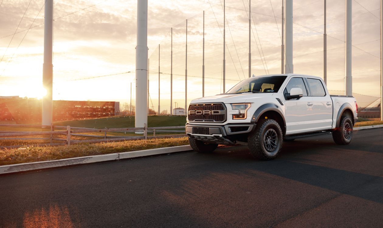 White Ford F-150 Raptor on a rural road at sunset